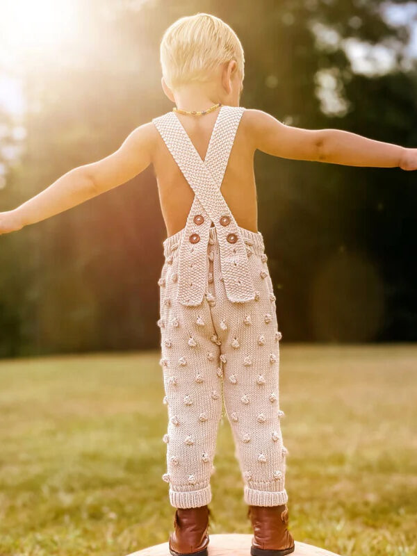 little boy wearing knitted overalls by JuneBee Baby ethical clothing brand