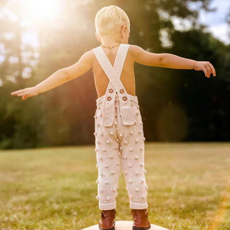 little boy wearing knitted overalls by JuneBee Baby ethical clothing brand