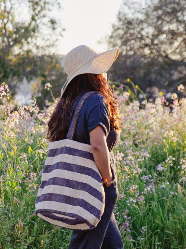 Woman in field wearing striped tote bag by fair trade brand Will + Atlas