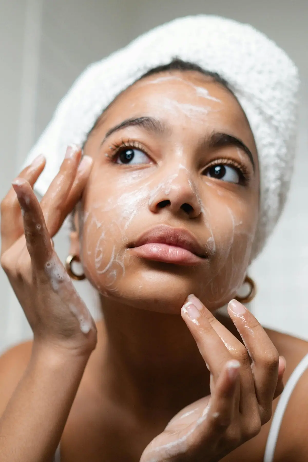 Woman applying moisturizer from refillable skincare brand