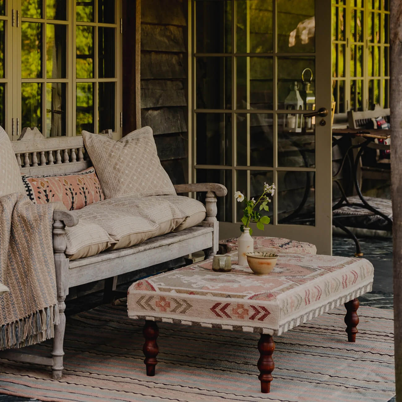 Weaver Green upcycled ottoman and woven pillows on patio